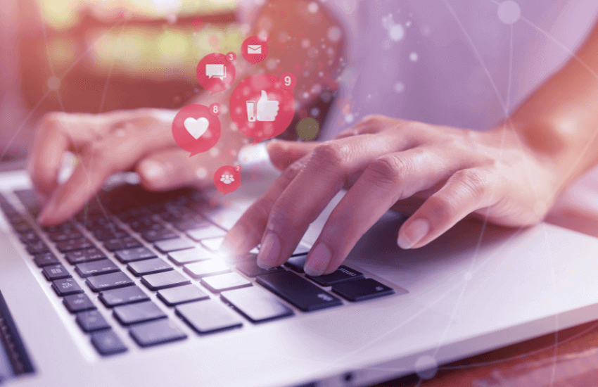 Redes sociales activas. Tecleando en un portátil del que salen iconos relacionados con las redes sociales