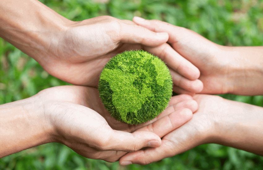 Manos sujetando un mundo verde lleno de vegetación